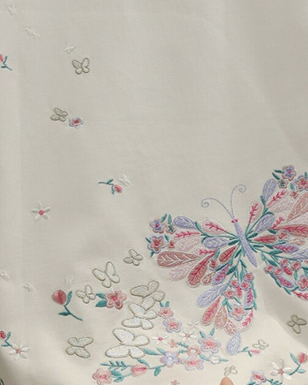 Close-up of the embroidered butterfly and blossoms on the white tee