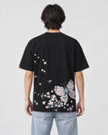 Model wearing the black butterfly embroidered T-shirt with light-wash jeans, back view