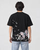 Model wearing the black butterfly embroidered T-shirt with light-wash jeans, back view