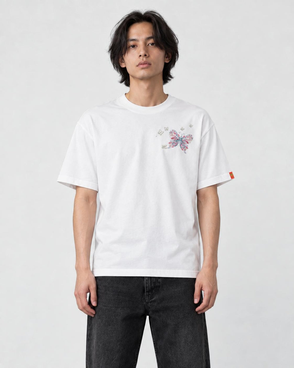Model wearing the white T-shirt with a small butterfly on the left chest, front view