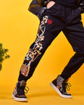 Model in mid-stride in the black joggers, with the pine tree embroidery running from the red seal to the pavilion