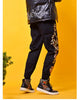 Black joggers worn with ankle boots, the pine tree embroidery and the pavilion visible on the outer leg