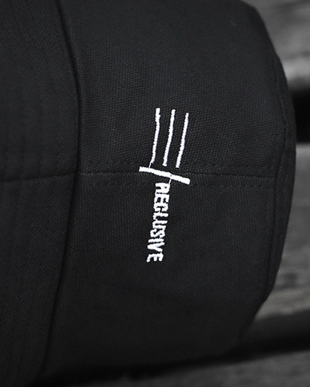 Close-up of the white three-line mark embroidered on the side of the hat
