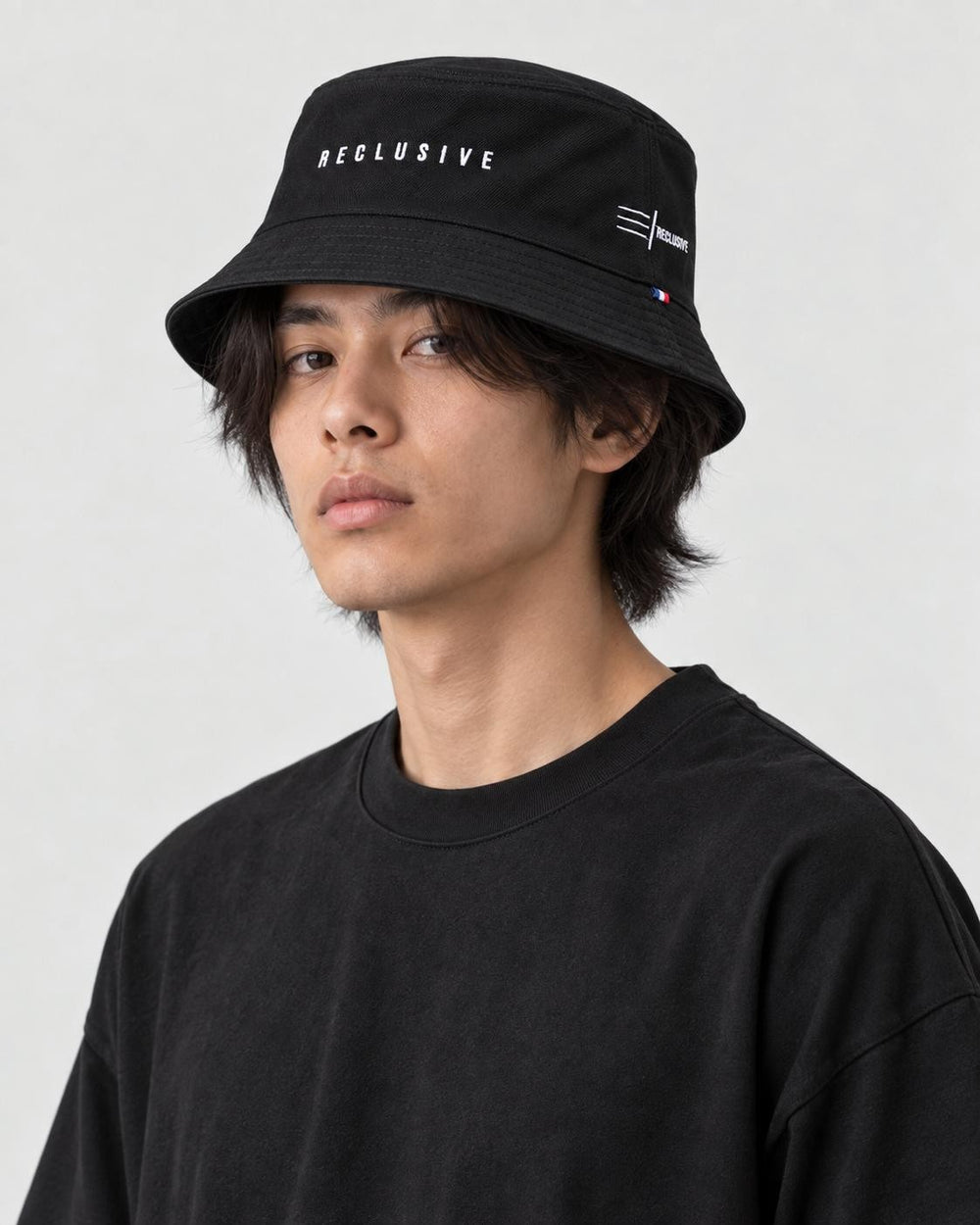Model wearing the RECLUSIVE bucket hat, three-quarter view