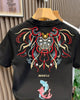 Back of the black T-shirt with a red, gold and teal embroidered mask, the word MIRACLE and two koi