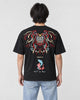 Man seen from behind in the black T-shirt with a large embroidered lion-dog mask, the word MIRACLE and two koi on the back