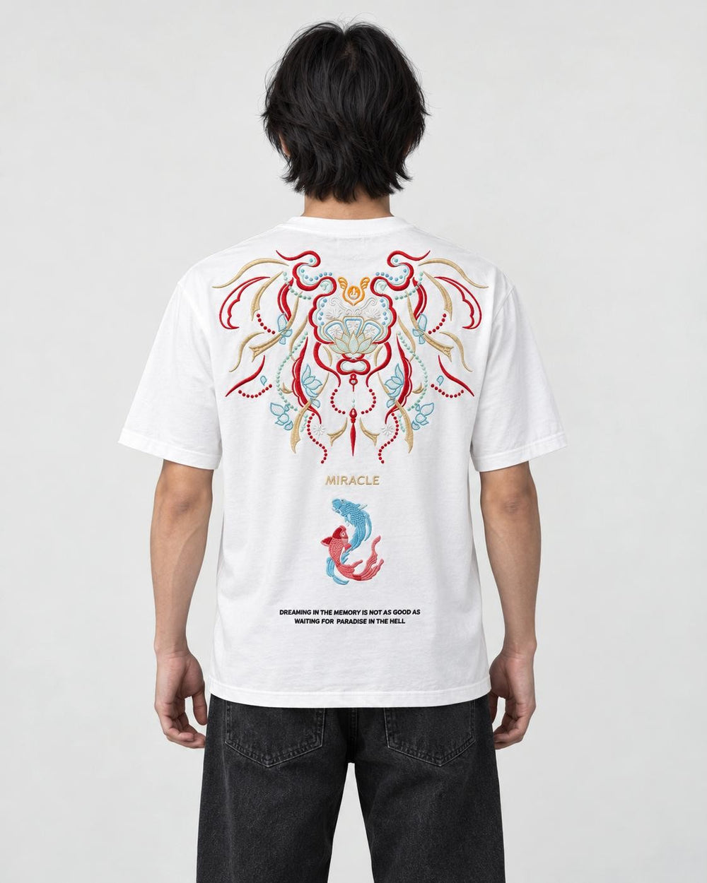 Man seen from behind in the white T-shirt with a large embroidered mask, the word MIRACLE and two koi on the back