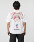 Man seen from behind in the white T-shirt with a large embroidered mask, the word MIRACLE and two koi on the back