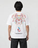 Man seen from behind in the white T-shirt with a large embroidered mask, the word MIRACLE and two koi on the back