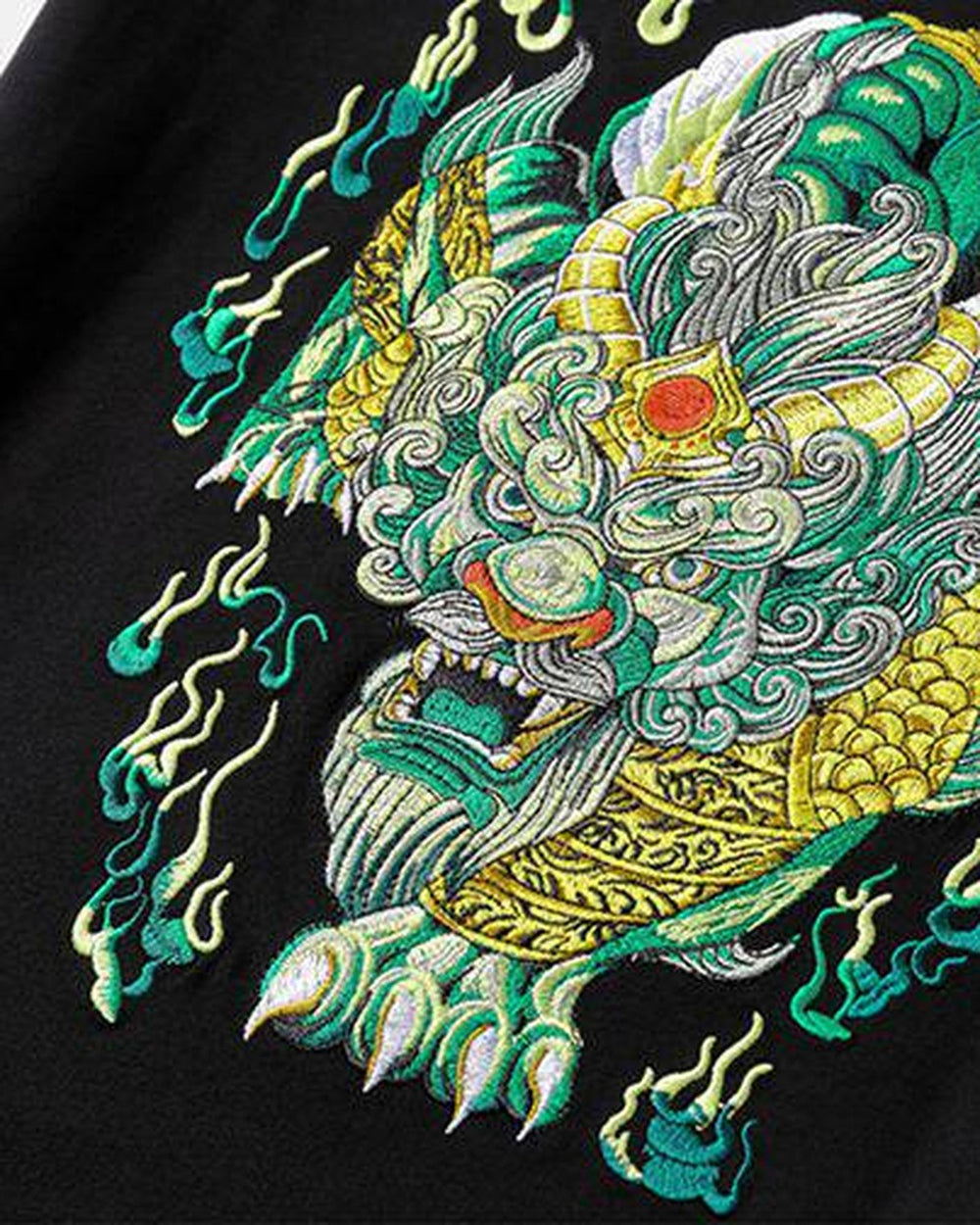 Close-up of the embroidered pixiu head in green, pale green and gold thread