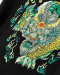Close-up of the embroidered pixiu head in green, pale green and gold thread