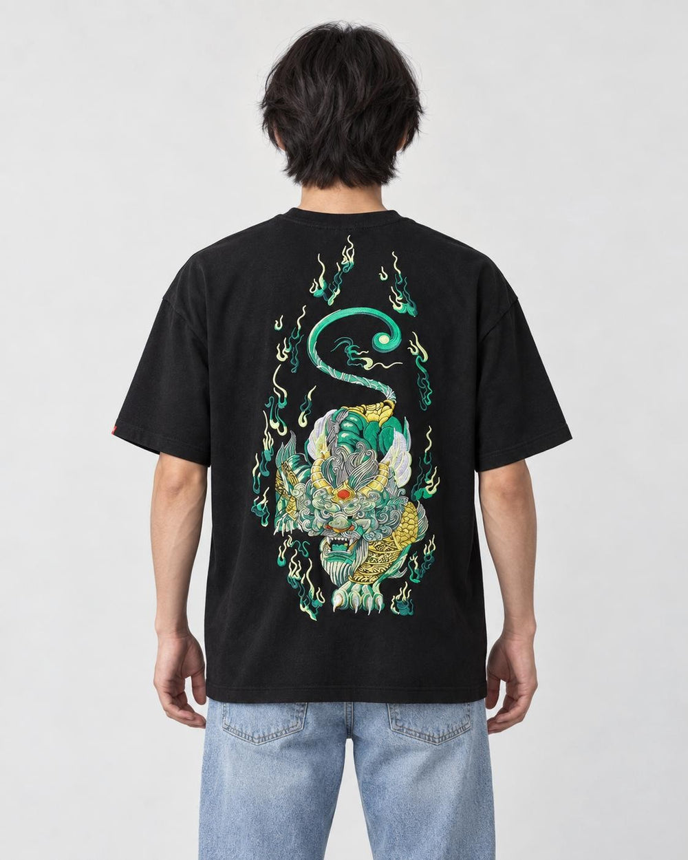 Model wearing the black pixiu embroidered T-shirt with light-wash jeans, back view