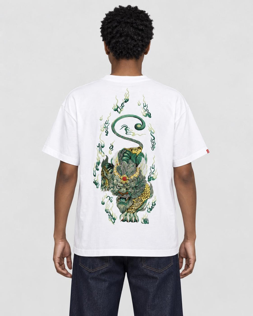 Model wearing the white pixiu embroidered T-shirt with dark jeans, back view