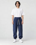 Model wearing navy harem pants with an embroidered sash and a white tee, front view