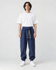 Model wearing navy harem pants with an embroidered sash and a white tee, front view