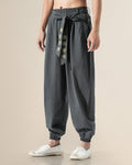 Dark gray harem pants with the embroidered sash tied in a bow, front view