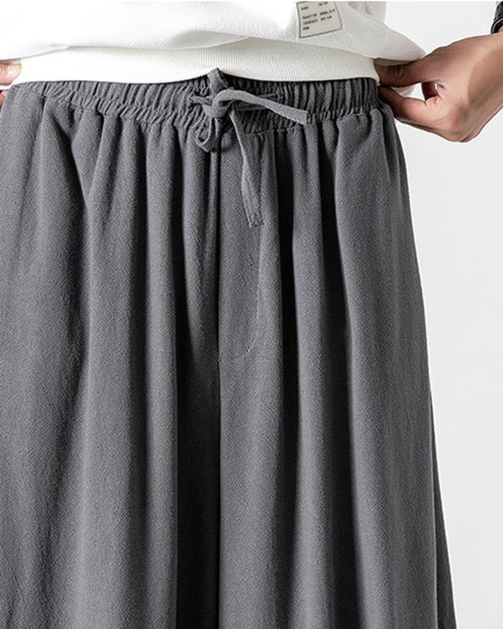 Close-up of the wide elastic waistband and the flat drawcord bow on the dark gray pants