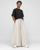 Model wearing the cream extra-wide linen-cotton skirt pants with a black tee and white sneakers, three-quarter view