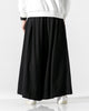 Black extra-wide linen-cotton skirt pants worn with a white sweatshirt and white sneakers