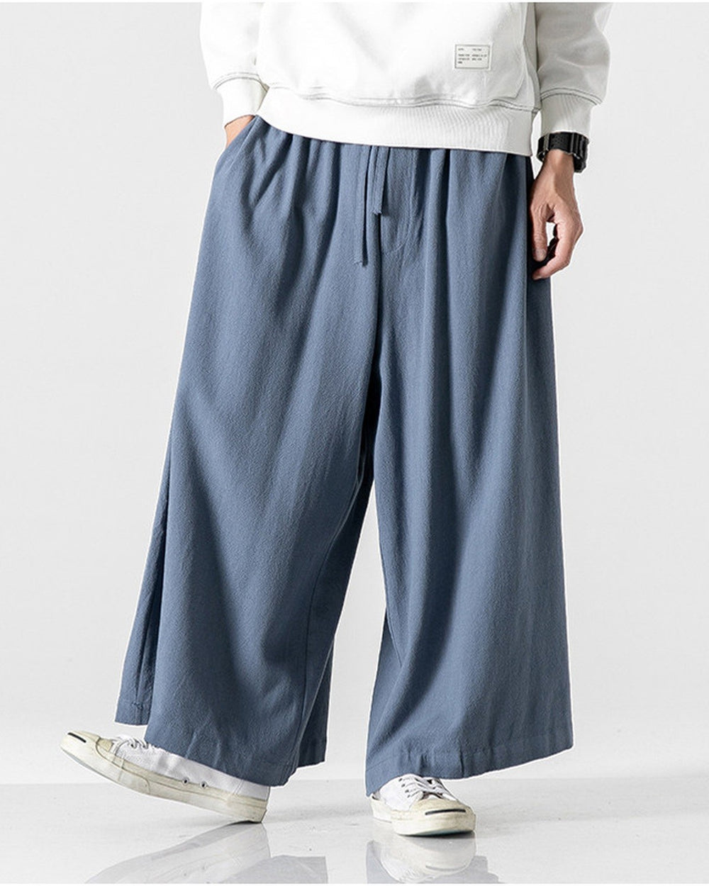 Steel blue extra-wide linen-cotton skirt pants worn with a white sweatshirt, mid-stride