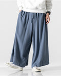 Steel blue extra-wide linen-cotton skirt pants worn with a white sweatshirt, mid-stride