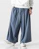 Steel blue extra-wide linen-cotton skirt pants worn with a white sweatshirt, mid-stride