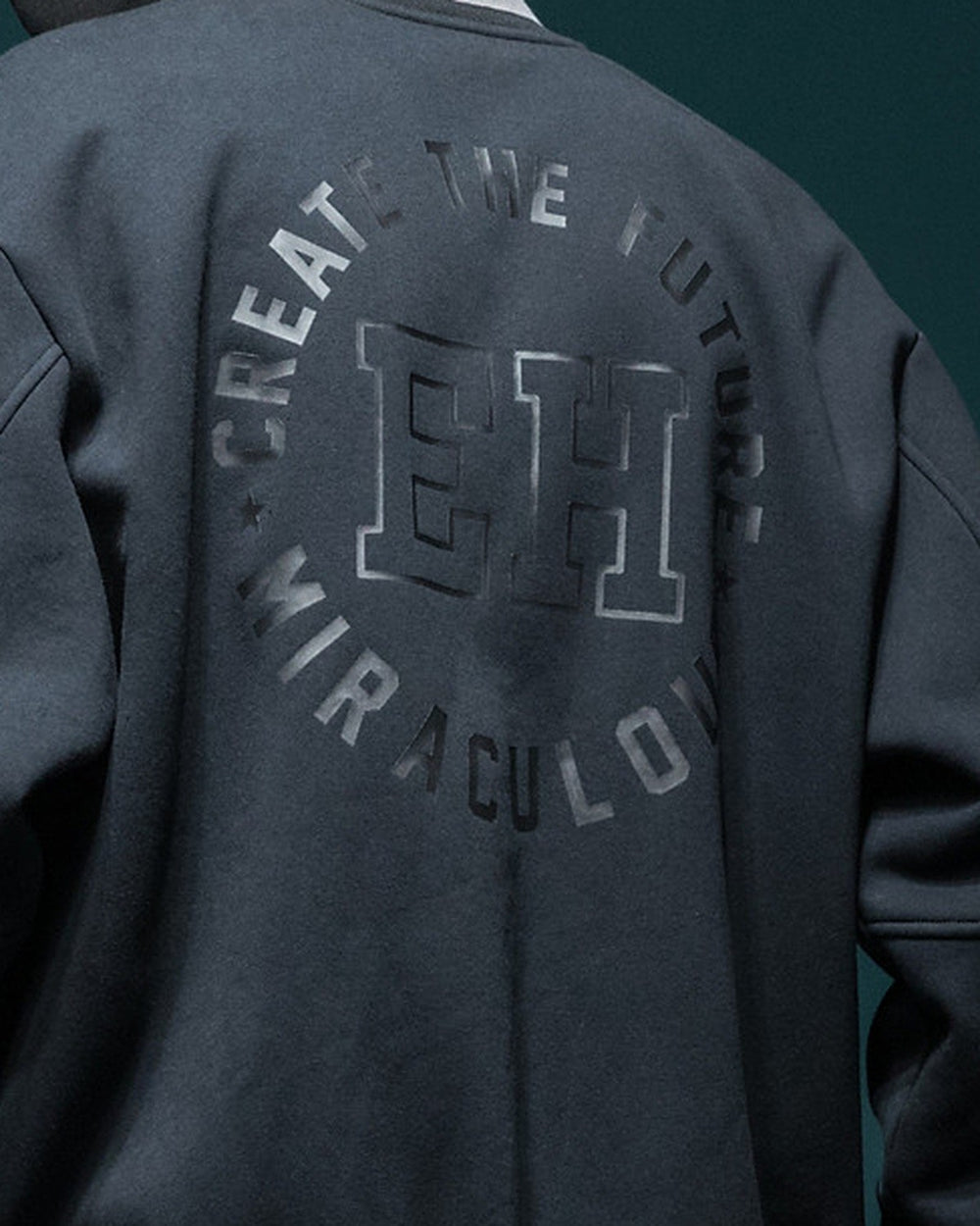 Close-up of the circular CREATE THE FUTURE, EH, MIRACULOUS print on the back of the dark jacket