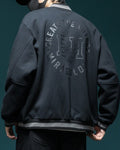 Back of the dark varsity jacket with the circular CREATE THE FUTURE, EH, MIRACULOUS print and the striped ribbed hem
