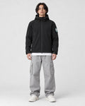 Model wearing the black softshell hooded jacket with gray cargo pants, front view