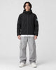 Model wearing the black softshell hooded jacket with gray cargo pants, front view