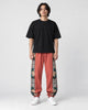 Model wearing the rust red floral embroidered jogger pants, front view