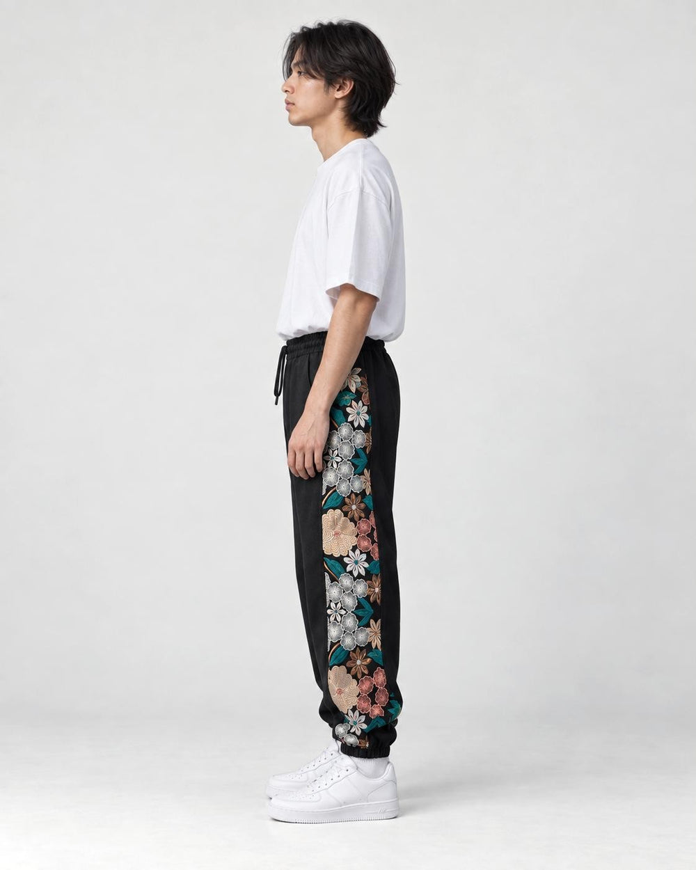 Model wearing the black jogger pants, side view of the floral embroidered panel