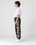 Model wearing the black jogger pants, side view of the floral embroidered panel