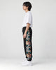 Model wearing the black jogger pants, side view of the floral embroidered panel