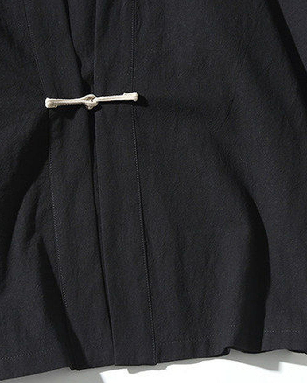 Close-up of the knotted frog toggle on the black jacket