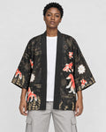 Model wearing the black goldfish and fireworks haori cardigan open over a white tee and stone trousers, front view