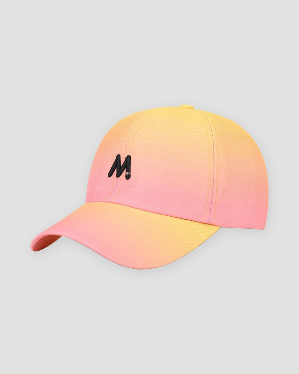 Baseball cap fading from peach to soft yellow, with a black M on the front