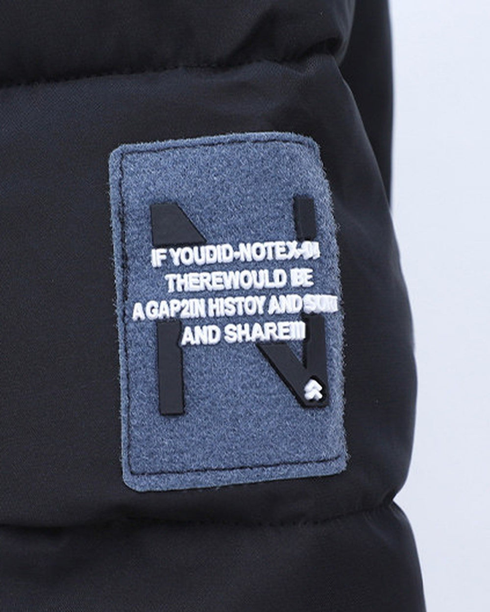 Close-up of the felt N badge on the upper sleeve of the black puffer jacket