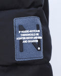 Close-up of the felt N badge on the upper sleeve of the black puffer jacket