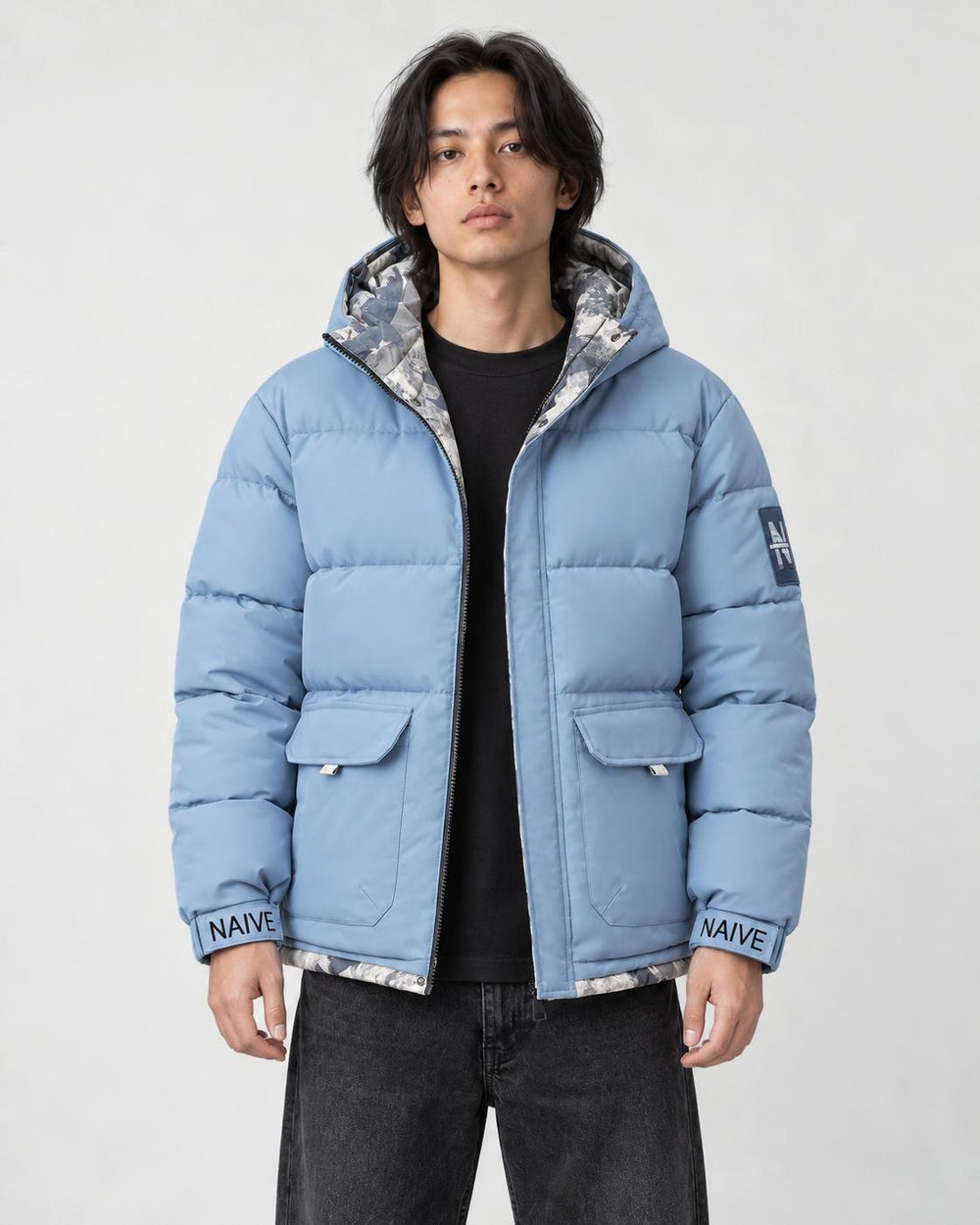 Model wearing the light blue puffer jacket with camouflage lining over a black tee, front view