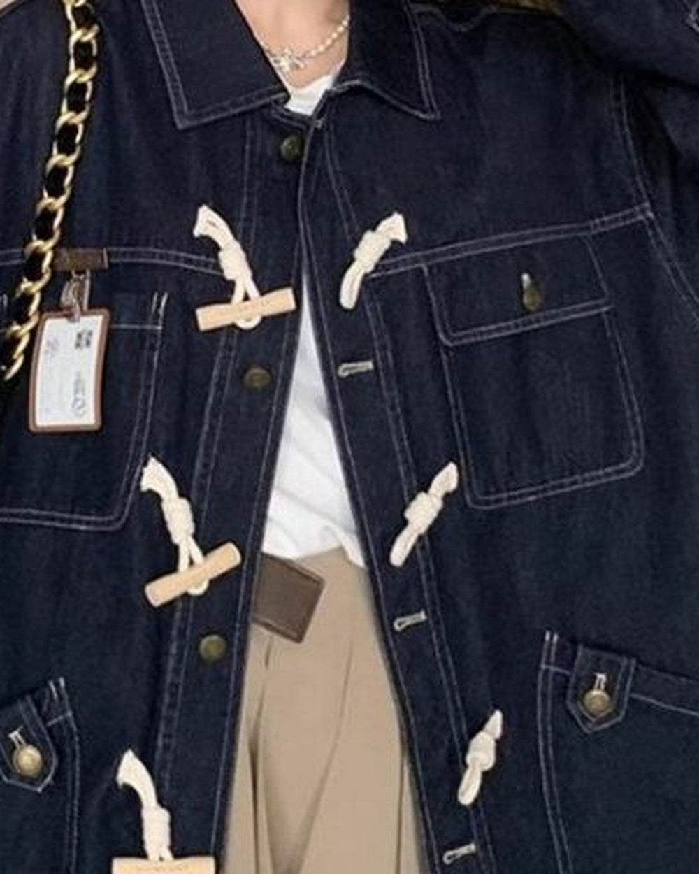 Close-up of the cream toggles, metal buttons, chest pocket and lower flap pockets on the dark indigo denim
