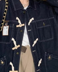 Close-up of the cream toggles, metal buttons, chest pocket and lower flap pockets on the dark indigo denim