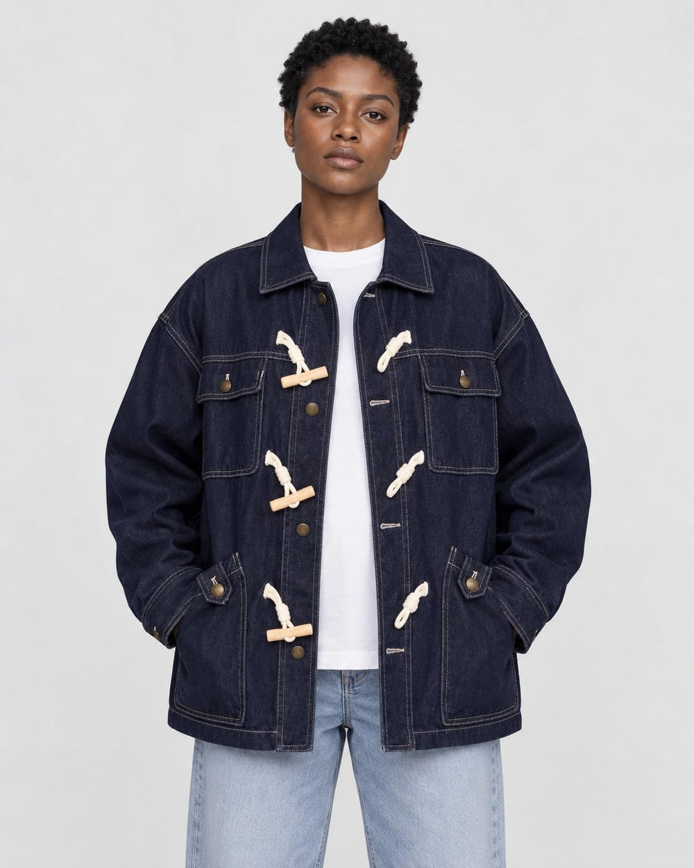 Model wearing the dark indigo horn toggle denim jacket over a white tee and light-wash jeans, front view
