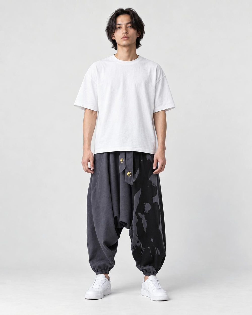 Model wearing the dark gray ink splash harem pants with a white tee, front view