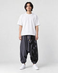 Model wearing the dark gray ink splash harem pants with a white tee, front view