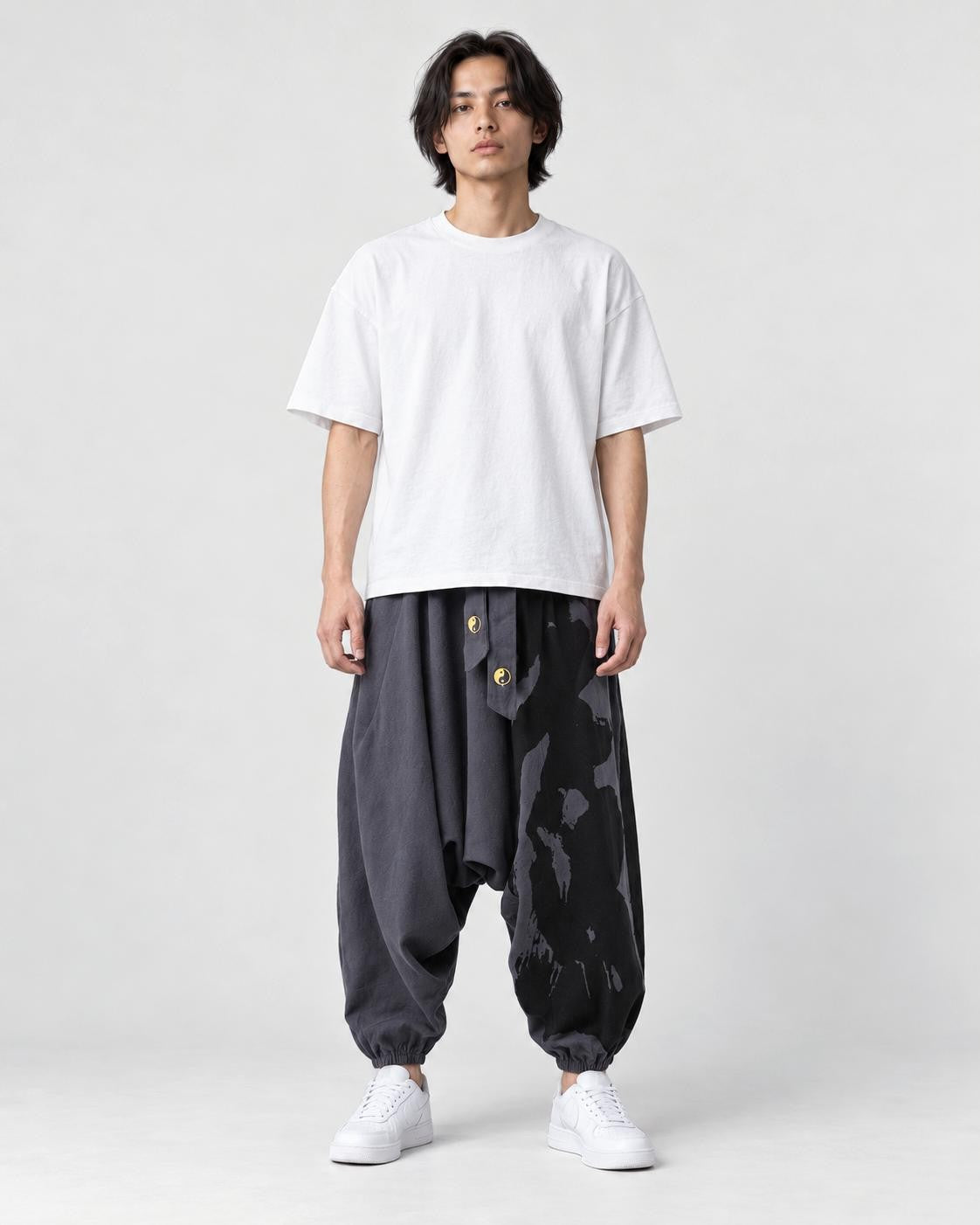 Model wearing the dark gray ink splash harem pants with a white tee, front view
