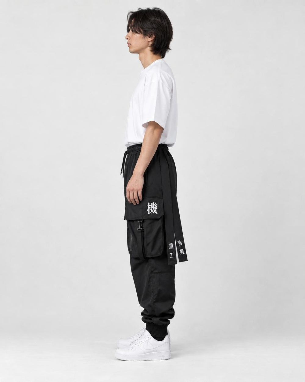 Model wearing the black cargo joggers, side view of the lettered hip straps