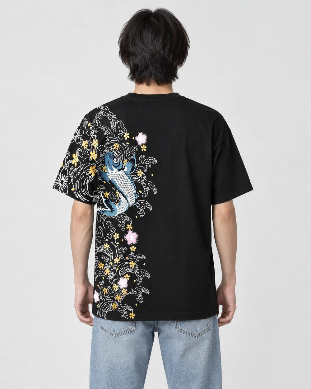 Man seen from behind in the black T-shirt with a koi, waves and plum blossoms down the left side of the back
