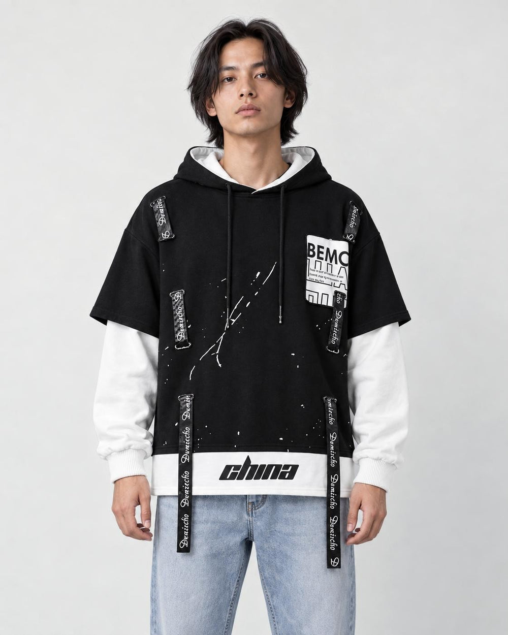 Model wearing the black layered hoodie with light-wash jeans, front view