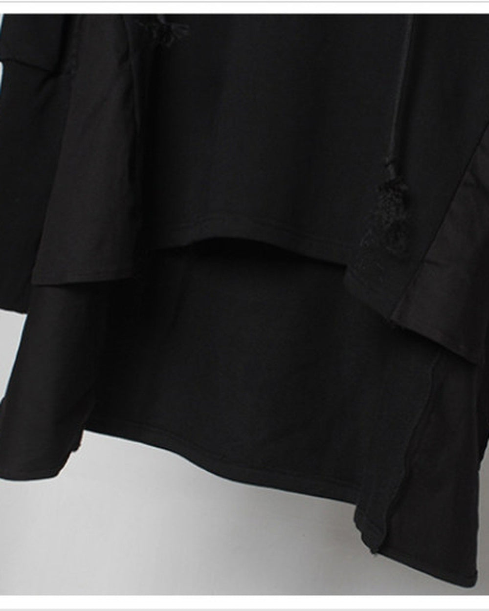 Close-up of the layered hem and the longer cape panel on the black hoodie